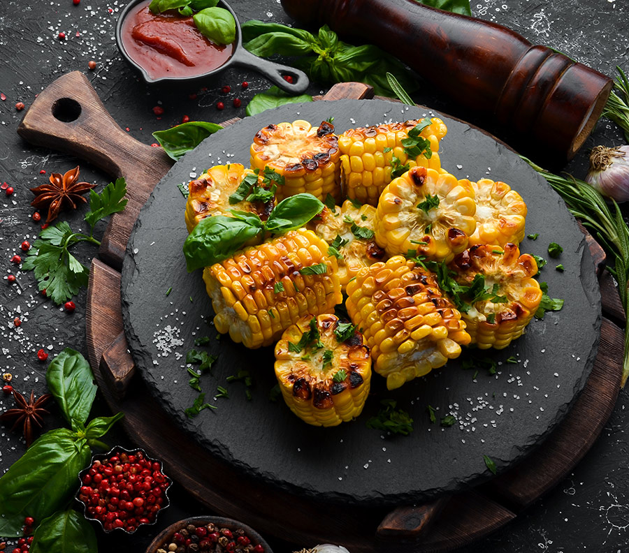 food-baked-corn-with-parsley-basil-black-stone-plate-top-view-free-space-your-text-cuadrada